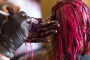 Hair dresser dying a woman's blond hair pink.